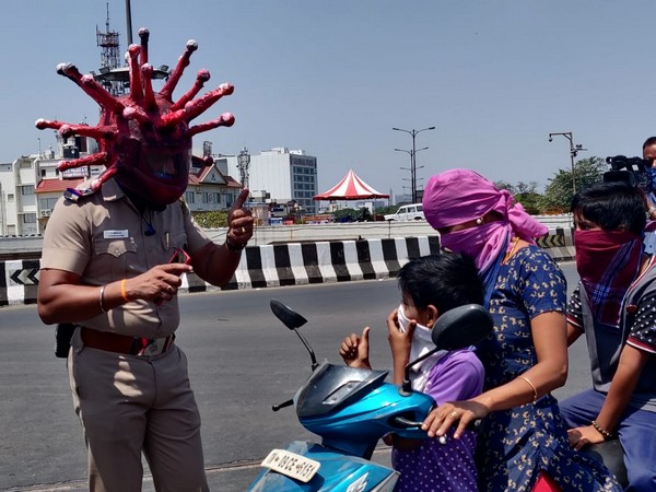 Inspector Rajesh Babu using the Corona helmet while talking to commuters in Chennai on Saturday. Photo/ANI