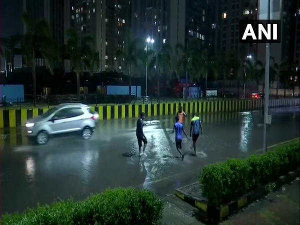 People play in the rain outside as heavy showers lash different parts of the city. Photo/ANI