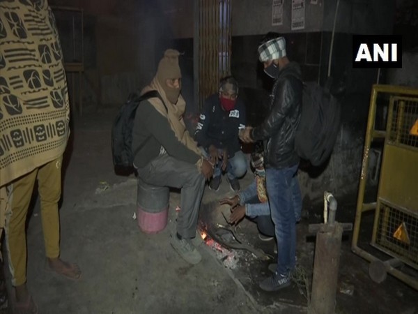 People sit near the fire to protect themselves from cold in Delhi's Anand Vihar (Photo ANI)