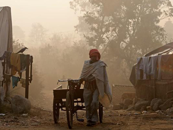 A man pulls a handcart on the banks of the Yamuna river on a foggy winter morning in New Delhi