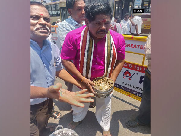 Kuppalji Devadoss carrying metal pot filled with coins worth Rs 25000 in Chennai on Monday.
