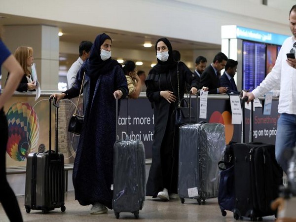 Travellers wear masks as they arrive at the Dubai International Airport   