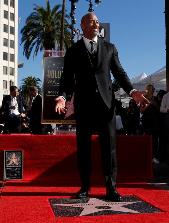 Actor Dwayne Johnson poses on his star after it was unveiled on the Hollywood Walk of Fame in Los Angeles, California, U.S., December 13, 2017