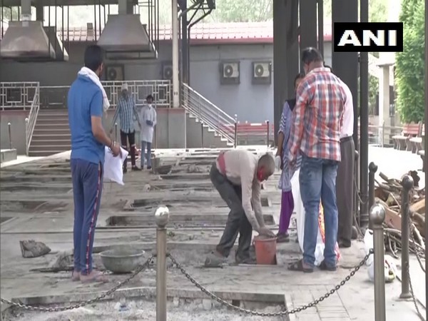 A worker collecting ashes at Nigambodh Ghat crematorium (Photo/ANI)