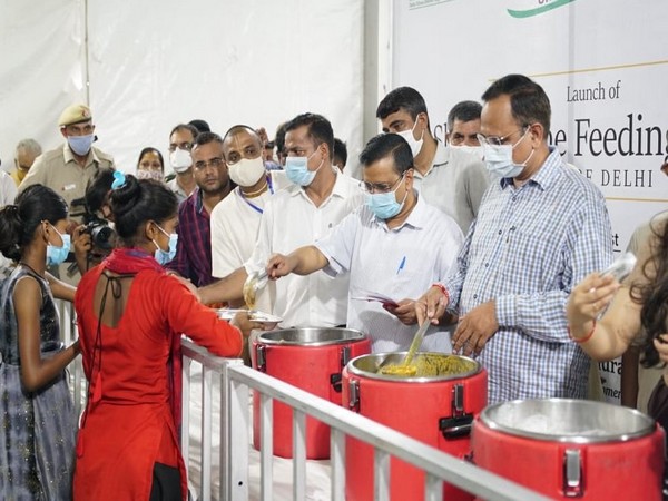 Delhi CM Arvind Kejriwal distributing food at Sarai Kale Khan. (Photo/ANI)