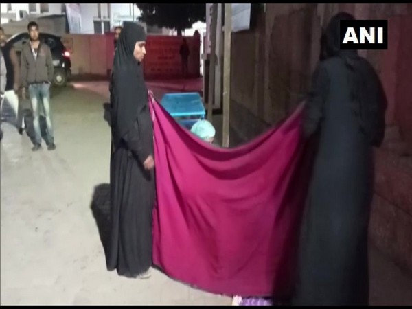 Family members covering Shafiq-un-nisa, as she delivers a baby outside government hospital premises in Bahraich. Photo/ANI