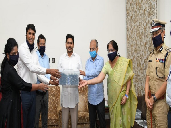 A visual of members of Self Help Groups handing over a box of masks to Chief Minister. 