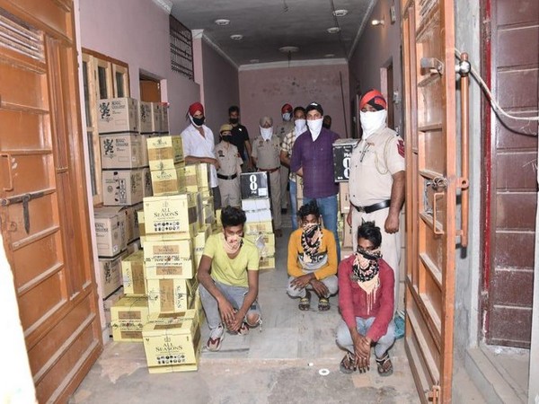 Punjab Police with the apprehended suspects and the seized cartons of liquor in Jalandhar on Thursday.