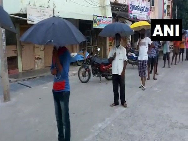 People use umbrellas to maintain social distancing outside liquor store in Guntur, Andhra Pradesh on Monday (Photo/ANI)