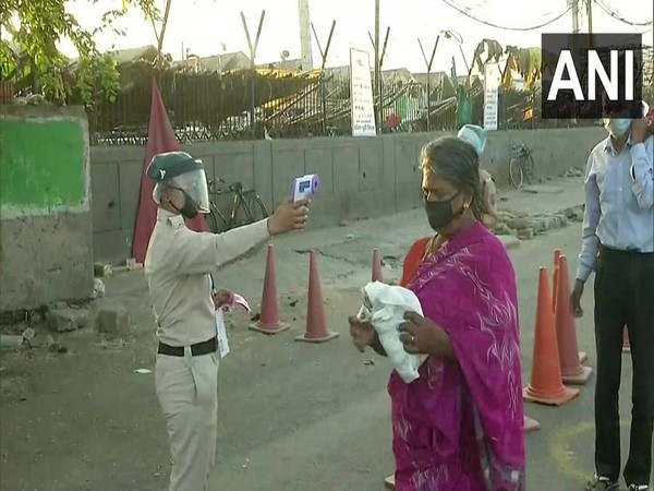 Police checking temperature of people at Okhla vegetable market. (Photo/ANI)