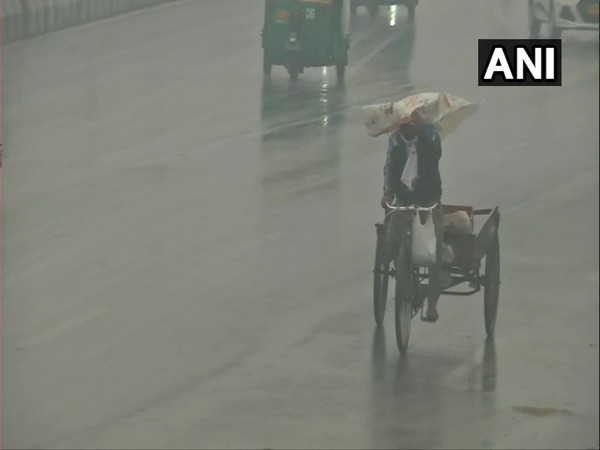 A rickshaw puller at the Ghazipur border covers his head to protect himself from the light showers. (Photo/ANI)
