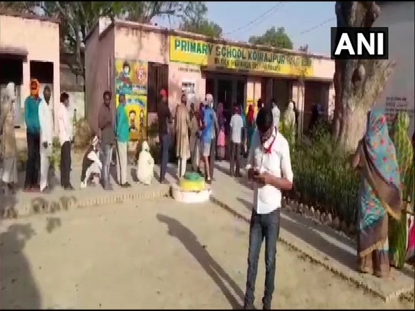 People standing in queue to cast vote for Panchayat polls at Koirajpur Primary School in Varanasi on Monday. (ANI)
