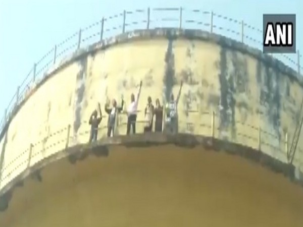 The Hardoi family atop the water tank on Sunday, threatening to commit suicide. (Photo/ANI)