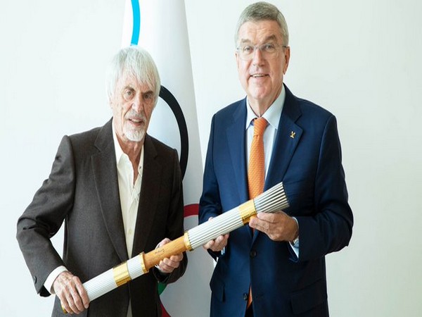 Bernie Ecclestone (L) handing the Olympic torch to Thomas Bach (R). (Photo/IOC Media Twitter)