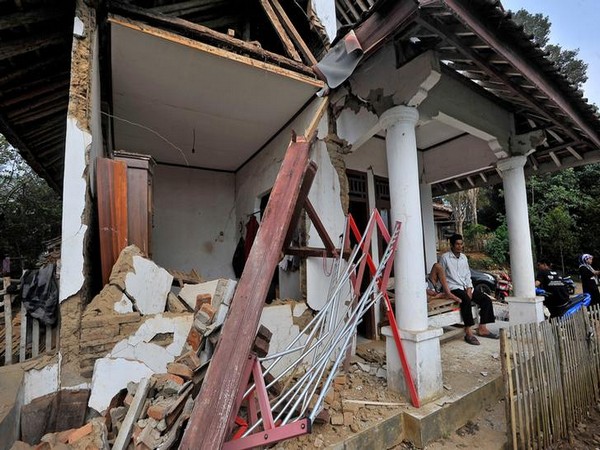 Locals sit at their house damaged after an earthquake hit in Pandeglang, Banten province, Indonesia, on Saturday