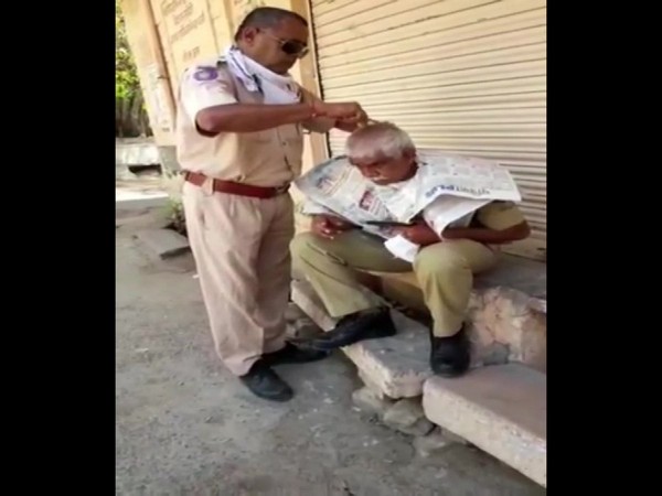 A policeman giving haircut to his colleague on duty in Jodhpur