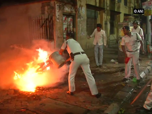 Policemen dousing a blaze following clashes during Amit Shah's roadshow in Kolkata on Tuesday. (Photo/ANI)