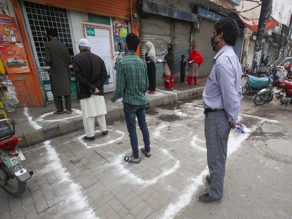 People stand in circles drawn with chalk to maintain safe distance outside a bank, during a lockdown
