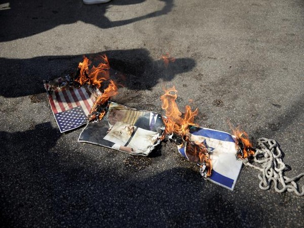 Representations of a US and Israeli flag and a picture of President Donald Trump are set on fire near the US Embassy in Awkar, Lebanon