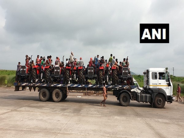 Migrant workers travel in trailer truck laden with tractors to reach home. (Photo/ANI
