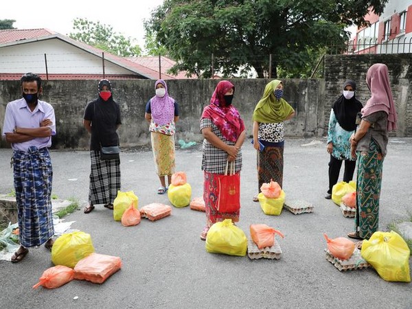 Rohingya refugees wearing protective masks wait for receiving goods from volunteers in Kuala Lumpur