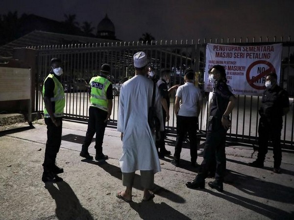 Police officers wearing protective masks stand guard outside the Seri Petaling Mosque, which has emerged as a source of hundreds of new coronavirus cases in Malaysia.