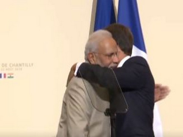 French President Emmanuel Macron and Prime Minister Narendra Modi pat each other during a joint interaction in Chantilly on Thursday
