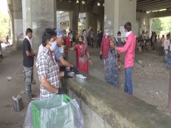 Rahul Tarun Mitra Mandal association volunteers giving food packets to migrant works staying under the Lokmanya Tilak terminus. Photo/ANI
