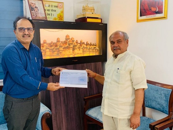 NAFED Managing Director Sanjeev Kumar Chadha handing over cheque to Union Agriculture Minister Narendra Singh Tomar. (photo/ANI)