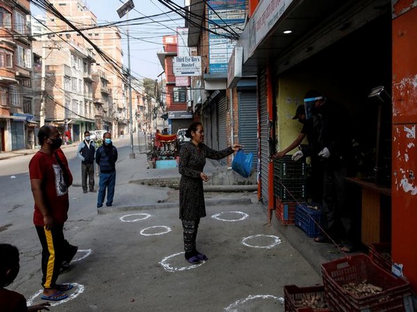 People stand on markings to maintain social distance as they buy vegetables on the fourth day of the lockdown imposed by the Nepali government