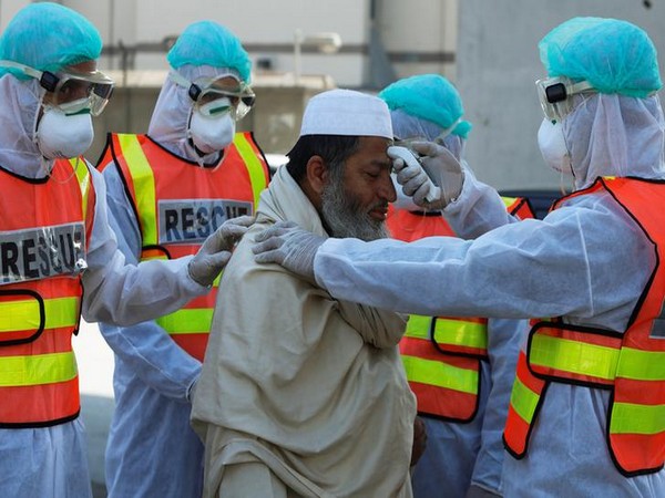 Rescue workers wearing masks and protective clothing check a man's temperature during a mock drill on handling suspected carriers of coronavirus in Pakistan