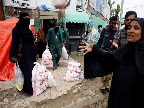 Pakistanis receive sacks of rationed food handouts from a distribution point of a charity welfare during a partial lockdown