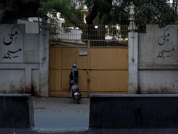 A man stands at the closed entrance of the Makki Masjid Tablighi center, after the government ordered to quarantine the center in Karachi