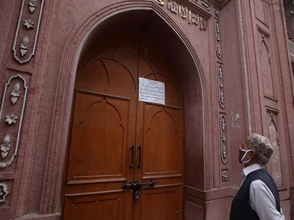 A man reads a notice, placed on the entrance door of a closed mosque during a lockdown in Peshawar