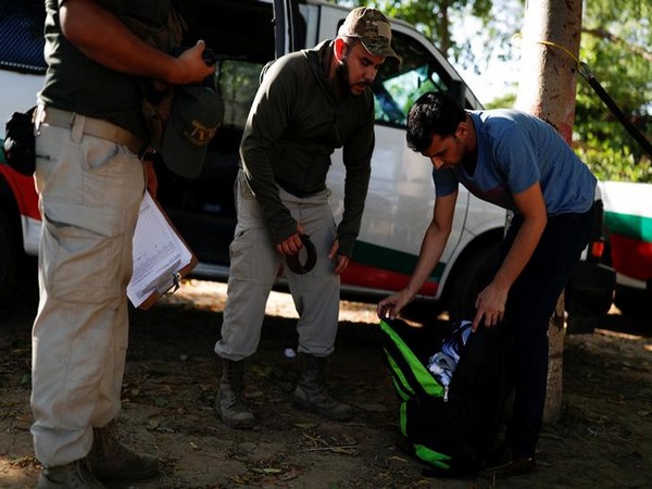 Mexican migration officers inspect the belongings of a Pakistani migrant after he was detained for not providing documentation in October 2018.