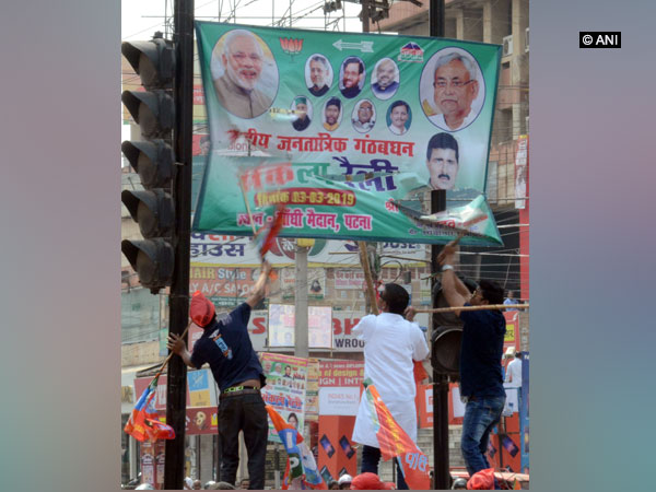 Quota supporters removing the banner of BJP-JDU in Patna on Tuesday. Photo/ANI   
