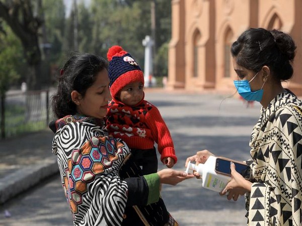 A volenteer offers hand sanitizer to a woman, as a preventive measure against the coronavirus