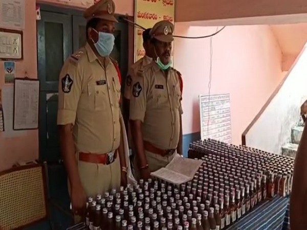 The police team in Krishna district with the seized liquor bottles. Photo/ANI