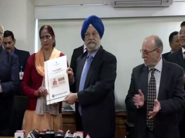 Union Minister Hardeep Singh Puri handing over the registry papers to the first beneficiary under PM-UDAY in New Delhi on Friday. Photo/ANI