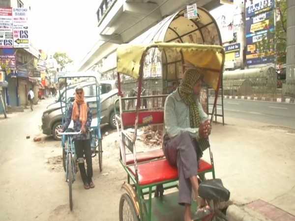 Two rickshaw pullers wait for customers amid lockdown in the national capital. Photo/ANI