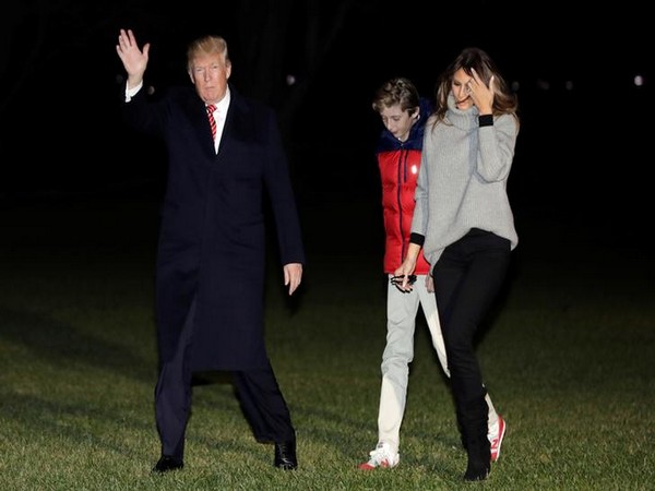 U.S. President Donald Trump waves as he walk with First Lady Melania Trump and their son Barron on the South Lawn of the White House