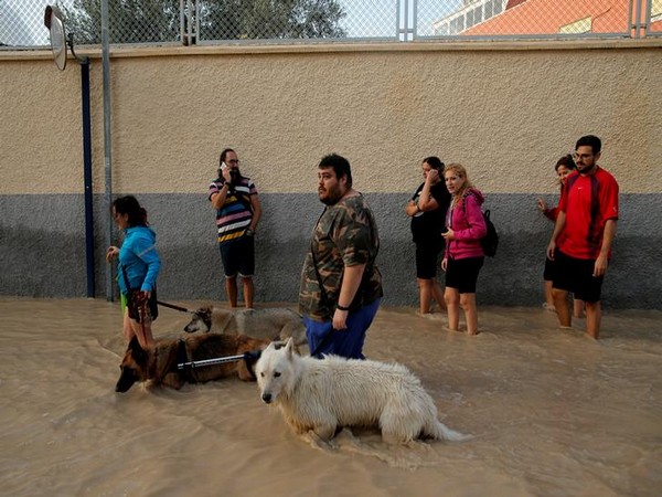 People wade through a flooded street as torrential rains hit Orihuela, Spain on September 13