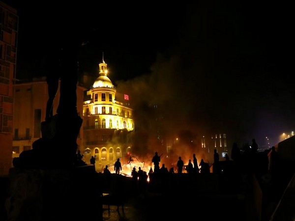 Protesters stand near burning tents during anti government protests in Beirut, Lebanon