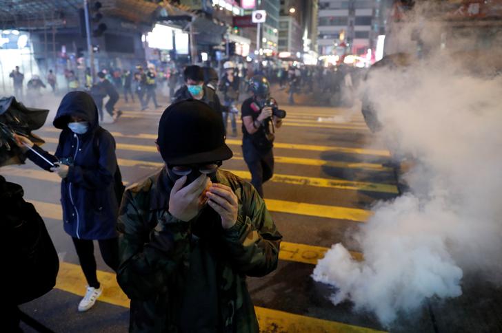 Anti-government protesters react to tear gas during a protest on Christmas Eve at Tsim Sha Tsui in Hong Kong,