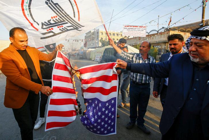 Iraqis burn US flag in protest after an airstrike at the headquarters of Kataib Hezbollah militia group in Qaim