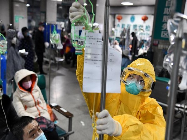 A medical worker in protective suit adjusts a drip bag for a patient at a hospital, following an outbreak of the new coronavirus in Wuhan