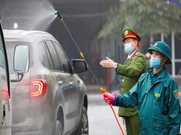 Members of anti-coronavirus team spray chemical into vehicles on a road in Vietnam's Thai Nguyen province