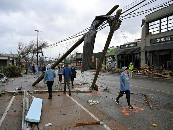 People walk past damaged power lines on Woodland Street after a tornado hit Nashville