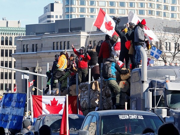Protestors stand on a trailer carrying logs as truckers and supporters take part in a convoy to protest COVID-19 vaccine mandates in Ottawa, Ontario, Canada, January 29. (Photo Credit: Reuters)