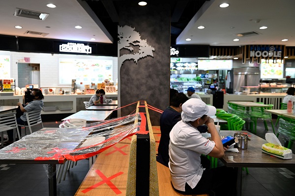 People dine at a food court with tables cordoned off as a safe distancing measure amid the coronavirus (COVID-19) Omicron wave in Singapore. (Photo Credit: Reuters)